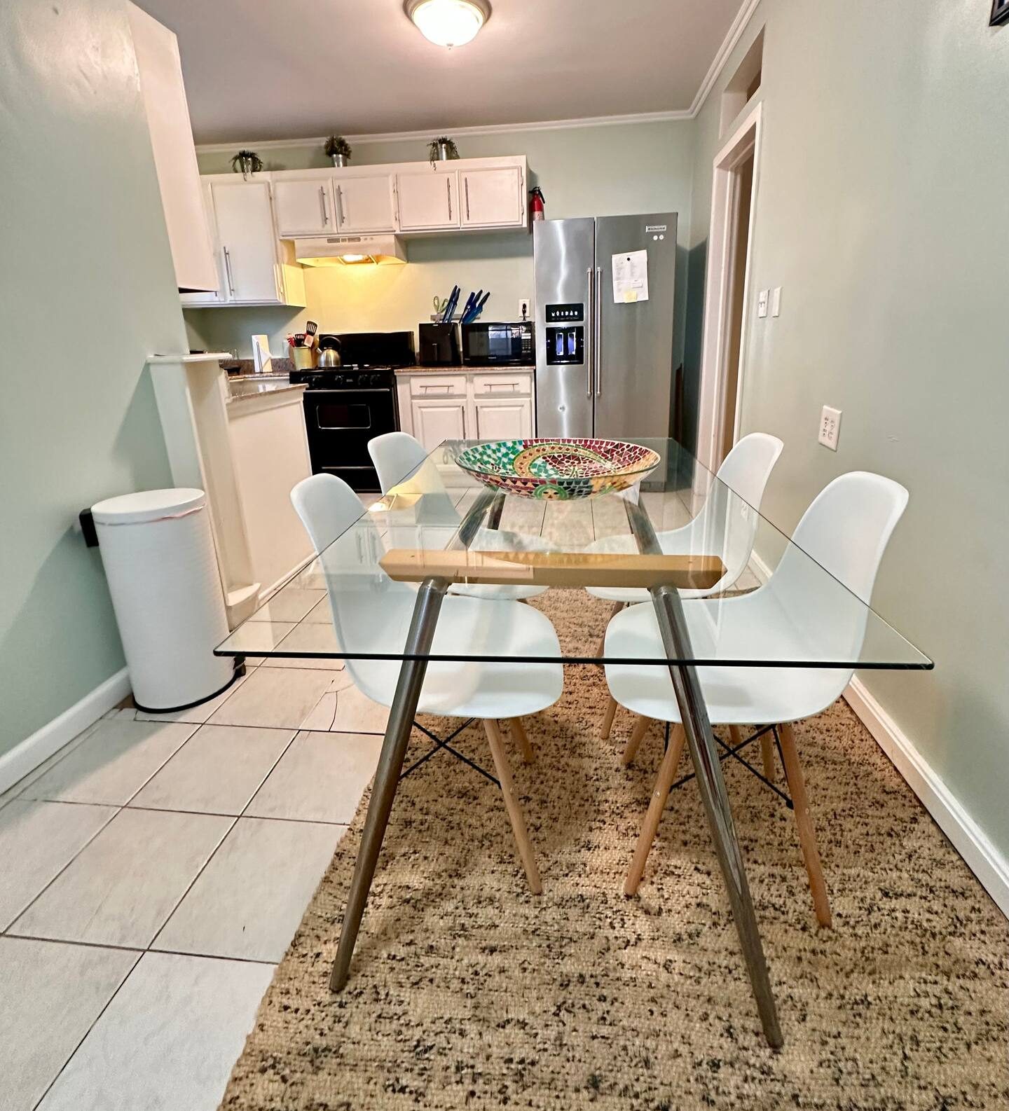 Glass dining table with white chairs by the kitchen