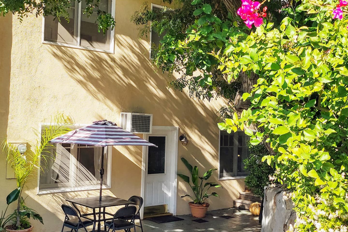 The courtyard under the bougainvillea, table and umbrella in the shade